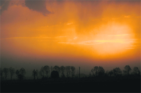 The sky turns orange as the sun sets on a cloudy day in Karnal. 
