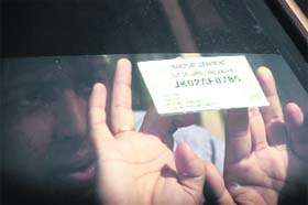 A transport department official pasting a unique third licence sticker on the windscreen of a car