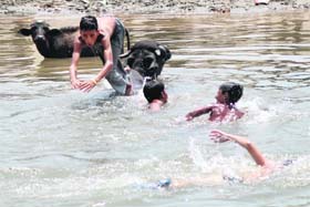 Children take a splash in Tawi river to get some respite from heat in Jammu on Monday