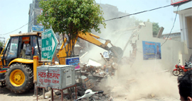 A Bathinda Municipal Corporation machine at work during the demolition drive being carried out on the Bibiwala Road in Bathinda on Tuesday.