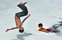 Children jumping into the Yamuna at Okhla Barrage to cool off in the scorching heat in New Delhi on Tuesday
