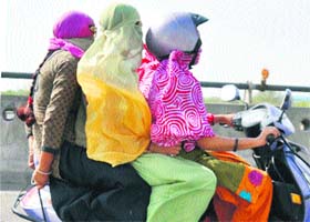 Girls cover their faces to protect themselves from the scorching sun on the NH-8 in Gurgaon
