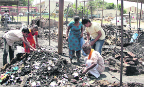 A poor family digs out half-burnt vegetables and fruits from the remains in Azad Sabzi Mandi, after it was gutted in fire on Wednesday.