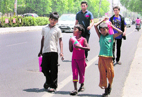 Children carry sweetened water on a sunny afternoon in Ludhiana.