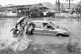 Passers-by push a vehicle through a water-logged road after heavy showers on Friday. 