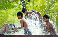 Children cool off in the muggy weather at India Gate 