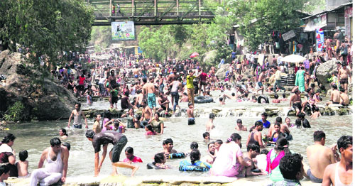 Tourists beat the heat at Sahastradhara in Dehradun on Sunday.