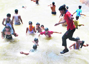Children enjoy a splash in the water on a hot summer day in Amritsar on Monday.