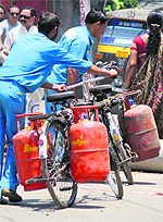 Workers carry LPG cylinders meant for domestic use on their bicycles in Jammu.