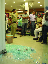 The smashed glass door of the showroom at Model Town in Jalandhar on Monday.