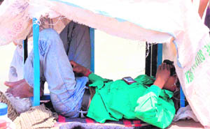 A man saves himself from searing heat by taking shelter under a jute bag cover near a Ganga ghat in Haridwar. 