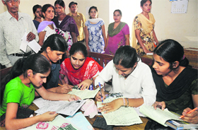 Students fill in admission forms at Government College for Women on Tuesday. 