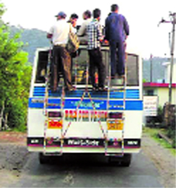 People travel on the roof top of a bus near Palampur.