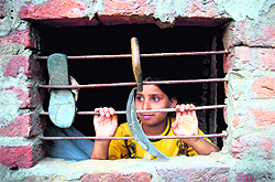 A girl  looks out of the window of her house