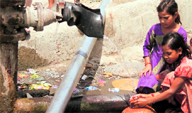 Girls collect water from a leaking pipeline on the outskirts of Jammu on Wednesday.