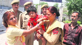 A police personnel hands over Gaurav (4) to his parents in Jammu on Wednesday.
