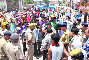 Policemen try to pacify agitated villagers who blocked Hansi road in protest against Ashoks murder in Karnal on Thursday.
