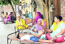 Women use hand fans during an unscheduled power cut while sitting outside their houses at the Bhargo Camp locality in Jalandhar on Thursday afternoon