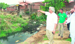 Dinesh Aggarwal, Planning and Sports Minister, examines a nullah in the Clementown area of Dehradun on Friday.