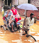A rickshaw-puller wades through a water-logged road after a heavy shower in Guwahati on Friday. 