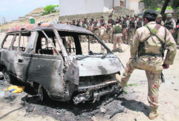 Afghan soldiers stand guard next to a burnt vehicle that was used to transport militants to the hotel on Friday.