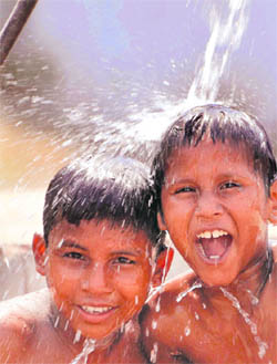 Children take a bath under the municipal water tap to beat the heat in Jammu on Saturday.