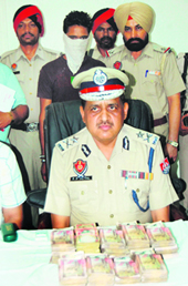 Police Commissioner RP Mittal shows the money recovered from Gurjeet Singh (with covered face) in Amritsar on Sunday. Photo: Vishal Kumar