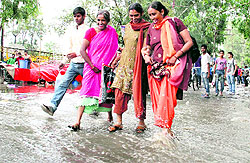 A group of women try to negotiate a flooded road after a downpour in Dehradun on Sunday