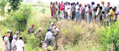 Policemen and villagers at the site where the girls body was found at Raipur Rasulpur village in Jalandhar on Sunday. 