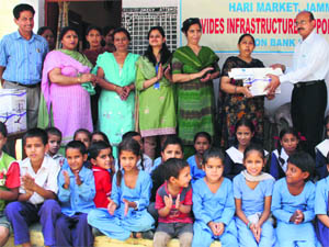 A bank official donates ceiling fans to Government Girls High School at Bhagwati Nagar in Jammu. 