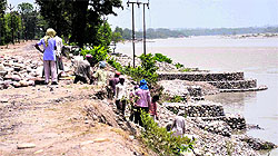Workers building flood bank embankments alongside Neel Dhara Ganga river in view of the damaged stretch in Haridwar on Thursday