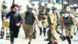 Security force personnel chase away protesters as they try to hold a march from Maisuma to Khanyar to mourn the Dastageer Sahib shrine fire in old Srinagaron Friday.