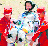 Chinas first female astronaut, Liu Yang, is carried by two retrieval crew members after she emerges from the Shenzhou-9 spacecraft on Friday