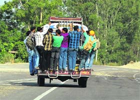 Youngsters clamber on to an overloaded mini bus on the Vijaypur-Jammu National Highway