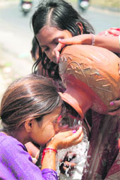 A girl drinks water from an earthen pitcher in Jammu. 