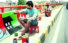 Artistes make paintings on the railway overbridge at the Circular Road in Rohtak.