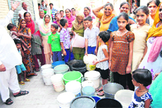 Residents of Santokhpura stand in a queue waiting for the arrival of a water tanker in Jalandhar 