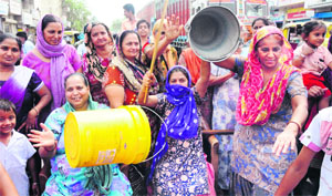 Women raise empty buckets during the blockade of the Karnal-Kaithal road at Shiv Colony in Karnal on Tuesday. 