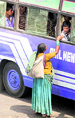 A woman becomes a traffic hazard as she seeks alms from a bus passenger on a busy Bikram Chowk in Jammu