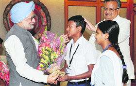 PM Manmohan Singh receives a bouquet from a boy during an interaction with students from Naxal-affected areas of Chhattisgarh, in New Delhi on Tuesday. Chhattisgarh CM Raman Singh is also seen.