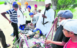 Children buy articles outside the venue for the state-level function of Shaheed Baba Maharaj Singh at Rabbon Uchhi village on Wednesday