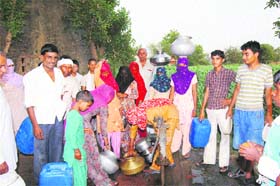 Residents await their turn for drinking water at Dighal village