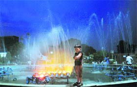 A child cools himself near a fountain at Mughal Canal on a hot evening in Karnal