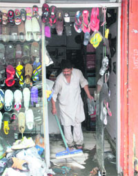 A  shopkeeper removes water from his shop in Jammu on Thursday. 