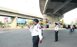 Traffic police personnel regulate vehicles under a flyover at BMC Chowk in Jalandhar.