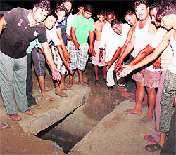 Residents point towards a wide gap between concrete slabs covering a sewerage drain in Sector 7 of Manesar