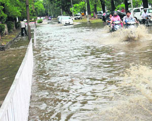 Commuters wade through a road in front of a girls hostel at Panjab University in Chandigarh on Saturday.