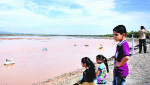 Children look on as tourists enjoy a boat ride after the water levels rose in Sukhna Lake, Chandigarh, following heavy rain on Saturday. 
