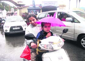 CAUGHT UNAWARES: A kid takes shelter under his umbrella as heavy rain lashes Mussoorie on Saturday