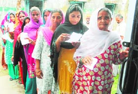 Women stand in a queue to cast their votes in Sitarganj on Sunday